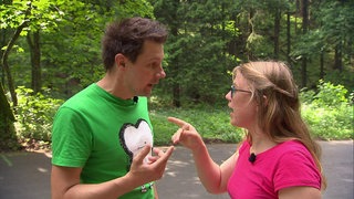 Ein Mann und eine Frau unterhalten sich und zeigen mit dem Finger aufeinander.